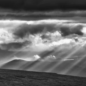 Sun rays fall through clouds in mountain landscape Sun rays fall through clouds in mountain landscape