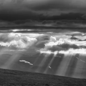 Sun rays fall through clouds in mountain landscape Sun rays fall through clouds in mountain landscape
