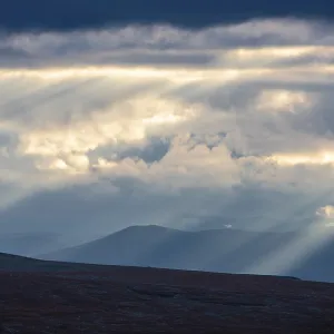Sun rays fall through clouds in mountain landscape Sun rays fall through clouds in mountain landscape