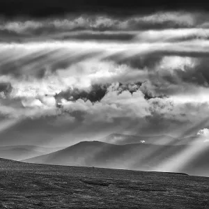 Sun rays fall through clouds in mountain landscape Sun rays fall through clouds in mountain landscape