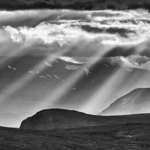 Sun rays fall through clouds in mountain landscape Sun rays fall through clouds in mountain landscape