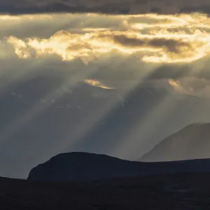 Sun rays fall through clouds in mountain landscape Sun rays fall through clouds in mountain landscape