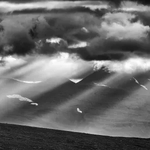 Sun rays fall through clouds in mountain landscape Sun rays fall through clouds in mountain landscape