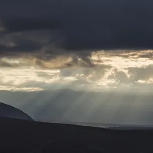 Sun rays fall through clouds in mountain landscape Sun rays fall through clouds in mountain landscape