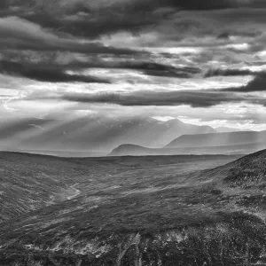 Sun rays fall through clouds in mountain landscape Sun rays fall through clouds in mountain landscape