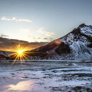 The sun rises behind snow-covered mountains and bathes the wintry landscape in warm light The sun rises behind snow-covered mountains and bathes the wintry landscape in warm light