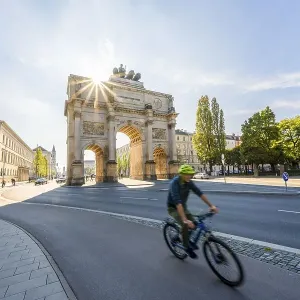 Sun star, Siegestor, cyclist riding along Leopoldstrasse