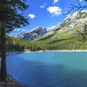 Sunlight illuminating the turquoise waters of lake minnewanka reflects the majestic canadian rockies