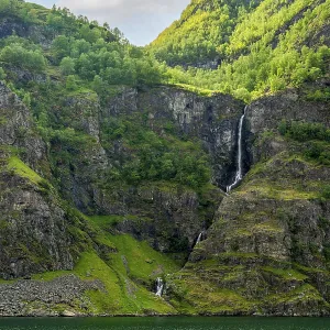 Sunlit panorama of Naeroyfjord with towering green mountains Sunlit panorama of Naeroyfjord with towering green mountains