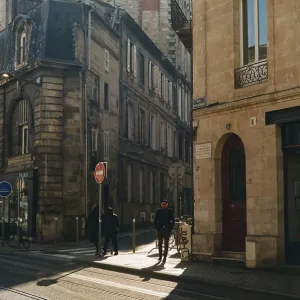 Sunlit street with historic buildings and people walking
