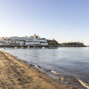 Sunrise on the Atlantic, skyline of a fishing village behind a harbour Sunrise on the Atlantic, skyline of a fishing village behind a harbour