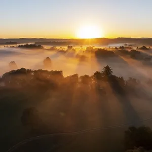 Sunrise with fog over cultivated landscape