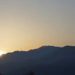Le lever du soleil sur une chaîne de collines et un pylône de transmission.