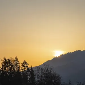 Le lever du soleil sur une chaîne de collines et un pylône de transmission.