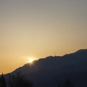 Le lever du soleil sur une chaîne de collines et un pylône de transmission.