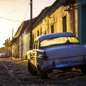 Sunset light in late afternoon shining on beautiful street with a white oldtimer in Trinidad Sunset light in late afternoon shining on beautiful street with a white oldtimer in Trinidad