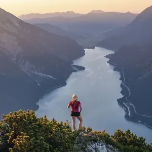 Sunset, young woman looking over mountain landscape Sunset, young woman looking over mountain landscape