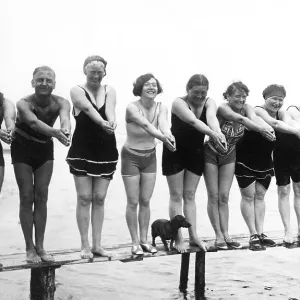 Swimwear, holidays, nine men and women and a dachshund posing on a jetty