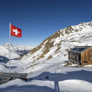 Swiss flag and mountain hut Keschhutte in front of mountain landscape in winter