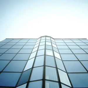 Symmetrical glass building with reflective surface and blue sky