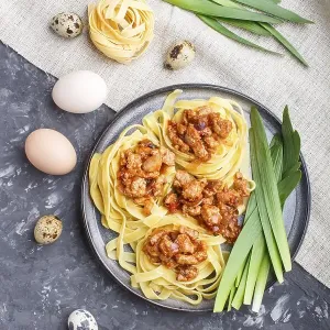 Tagliatelle bolognese pasta with minced meat on a black concrete background Tagliatelle bolognese pasta with minced meat on a black concrete background
