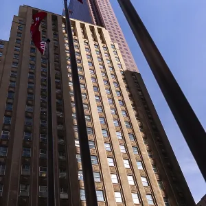 Edificio alto con banderas contra un cielo azul claro en un entorno urbano en Toronto, Ontario, Canadá.