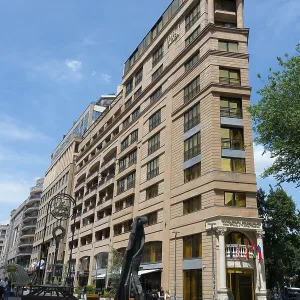 Tall building in an urban environment with a unique statue in front of it
