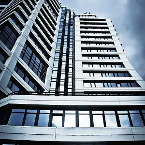 A tall, modern building with glass windows against a cloudy sky