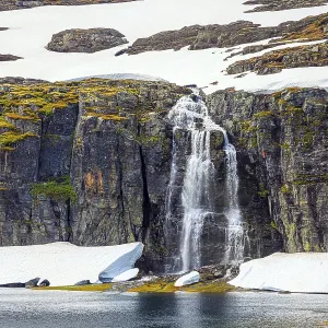 Tall waterfall falls into the lake