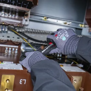 A technician uses tools for maintenance work inside a switch box