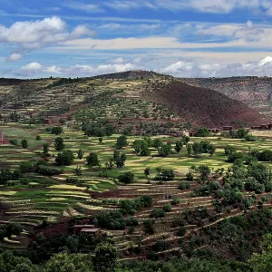 Terraced fields in a hilly landscape of the High Atlas Mountains under wide skies