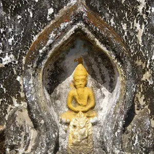 Theravada Buddhism, detail of yellow Buddha figure in meditation posture Theravada Buddhism, detail of yellow Buddha figure in meditation posture