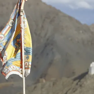 Tibetan Buddhist prayer flag with Namgyal Tsemo Buddhist monastery surrounded by mountains and sky Tibetan Buddhist prayer flag with Namgyal Tsemo Buddhist monastery surrounded by mountains and sky
