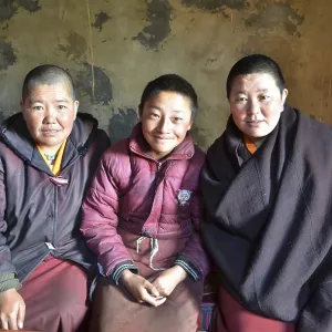 Three Tibetan nuns sitting in the kitchen of the nunnery in the mountains of Reting Monastery