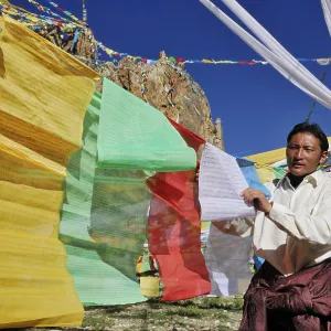 Tibetan pilgrim hanging prayer flags for the upcoming ceremony on Namtso Lake