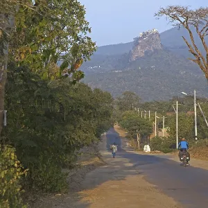 Tourist cycling towards Buddhist monastery on the summit of Taung Kalat near the volcano Mount Popa Tourist cycling towards Buddhist monastery on the summit of Taung Kalat near the volcano Mount Popa