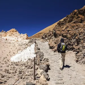 Tourist man with backpack going to the top of the volcano Teide in Tenerife