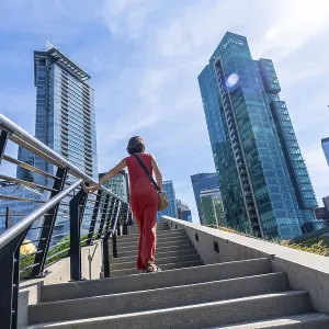 Tourist walking up stairs with skyscrapers and modern architecture in the background