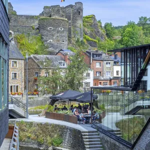 Tourists at restaurant along the river Ourthe and ruined castle in the city La Roche-en-Ardenne Tourists at restaurant along the river Ourthe and ruined castle in the city La Roche-en-Ardenne