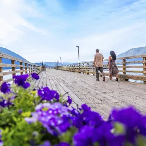 Tourists walking on a wooden pier adorned with vibrant flowers Tourists walking on a wooden pier adorned with vibrant flowers