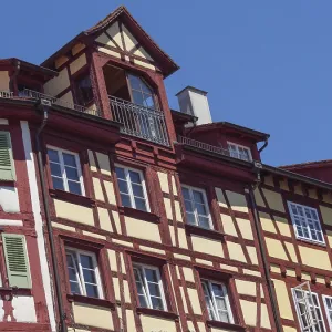 Traditional half-timbered house with red and yellow elements against a blue sky