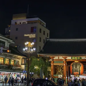 A traditional Japanese temple next to a busy street at night A traditional Japanese temple next to a busy street at night