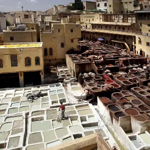 Traditional leather tannery in Fez with numerous paint basins and surrounding ancient architecture