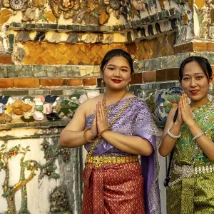 Traditionally dressed woman pose in front of the temple Wat Arun or Temple of Dawn in Bangkok