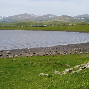 Tranquil lake with a view of green hills and distant mountains on the horizon
