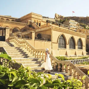 Traveler woman in white dress walking stairs of historic building - visit Mardin museum in old city of Mardin Turkey