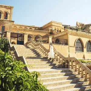 Traveler woman in white dress walking stairs of historic building - visit Mardin museum in old city of Mardin Turkey