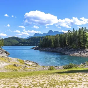 Turquoise waters of lake minnewanka reflecting a sunny sky with fluffy clouds