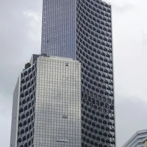 Unique skyscraper with modern glass facade in an urban setting under cloudy sky Unique skyscraper with modern glass facade in an urban setting under cloudy sky