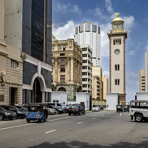 Urban street full of vehicles surrounded by modern and historic buildings under blue skies